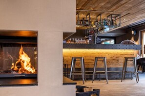A bar area with a wooden ceiling, a fireplace, and a bar counter with stools. - Wifi, resort center, tv, ski locker, 34-41m², Zinal (Zinal)