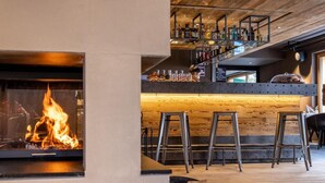 A bar area with a wooden ceiling, a fireplace, and a bar counter with stools. - Wifi, resort center, tv, ski locker, 57-67m², Zinal (Zinal)