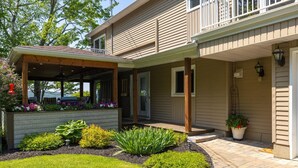 A two-story house with a covered porch, a landscaped garden, and a small outdoor seating area. - La Brise O-Lac (Sherbrooke)