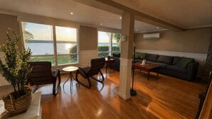 A spacious living room with wooden flooring, a sofa, a coffee table, and a potted plant. - La Brise O-Lac (Sherbrooke)