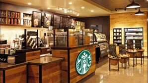 A Starbucks coffee shop interior with wooden counters, a menu display, and seating areas.