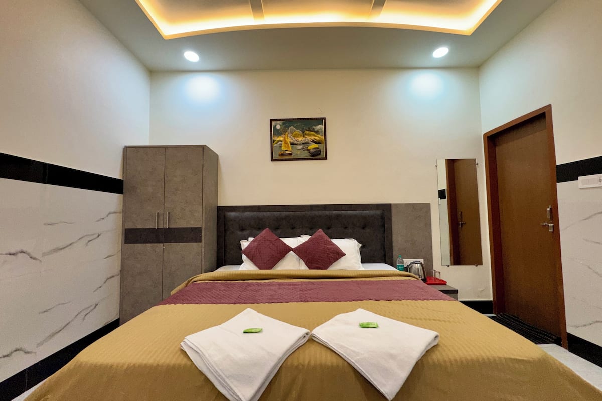 A hotel room with a bed, a wardrobe, a painting on the wall, and a door.