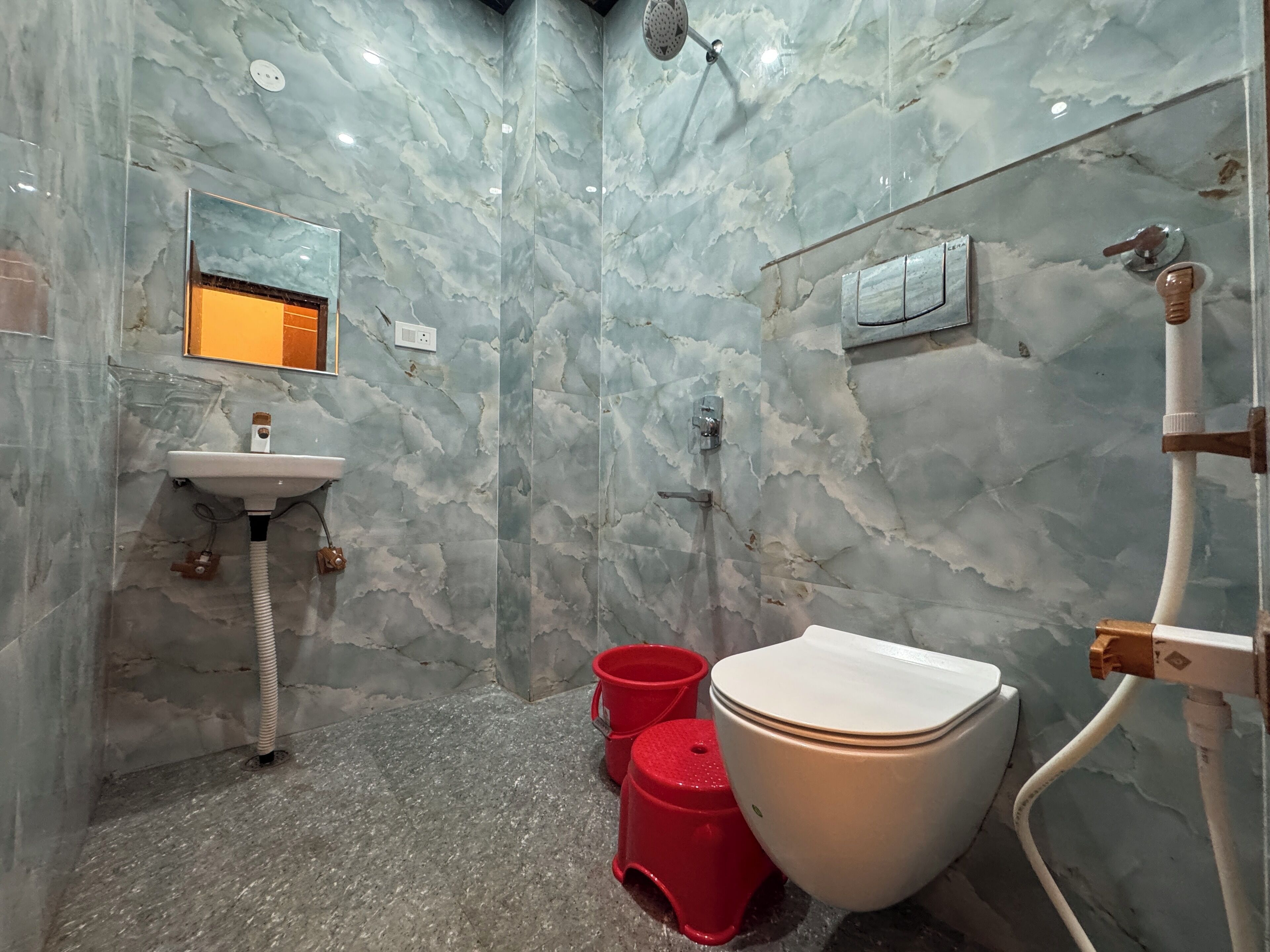 Une salle de bain avec un mur en marbre, un lavabo, des toilettes et une douche.