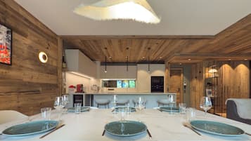 Un espace repas moderne avec une table en marbre blanc, des assiettes de couleur turquoise et un luminaire suspendu original orné de plumes.