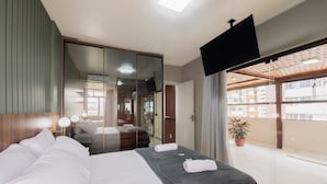 Habitación de hotel moderna con una cama grande, un televisor y un balcón con vistas a la ciudad.