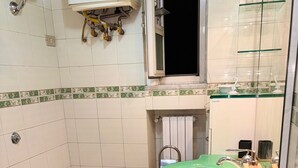Een badkamer met twee toiletten, een wastafel, een toiletrolhouder en een douche.
