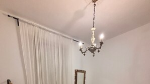 Een slaapkamer met een bed, een hanglamp, een spiegel en een bureau.
