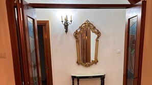 Een gang met een patroon vloer, een spiegel aan de wand en een klein tafeltje.