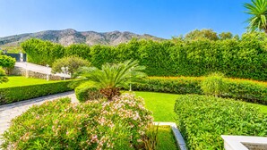 A landscaped garden with manicured hedges, a pathway, and a mountain backdrop.