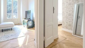 A spacious room with a large window, a white door, and a herringbone-patterned wooden floor. - Design & Comfort in Porta Romana (Milan)