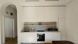 A modern kitchen with white cabinetry, a built-in oven, and a countertop with a coffee maker and other appliances. - Design & Comfort in Porta Romana (Milan)