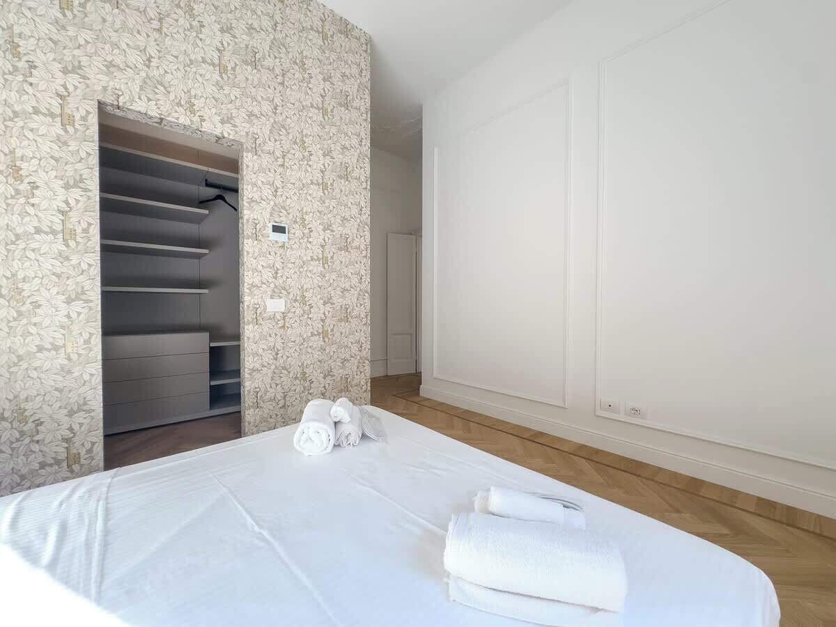 A hotel room with a bed, a wardrobe, and a door.