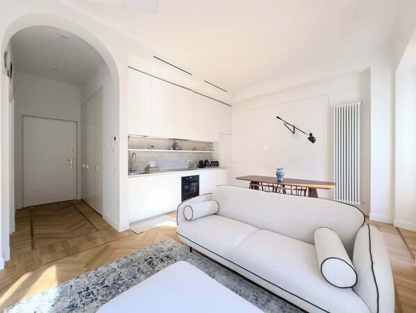 Una sala moderna con sofá, mesa de comedor y zona de cocina.
