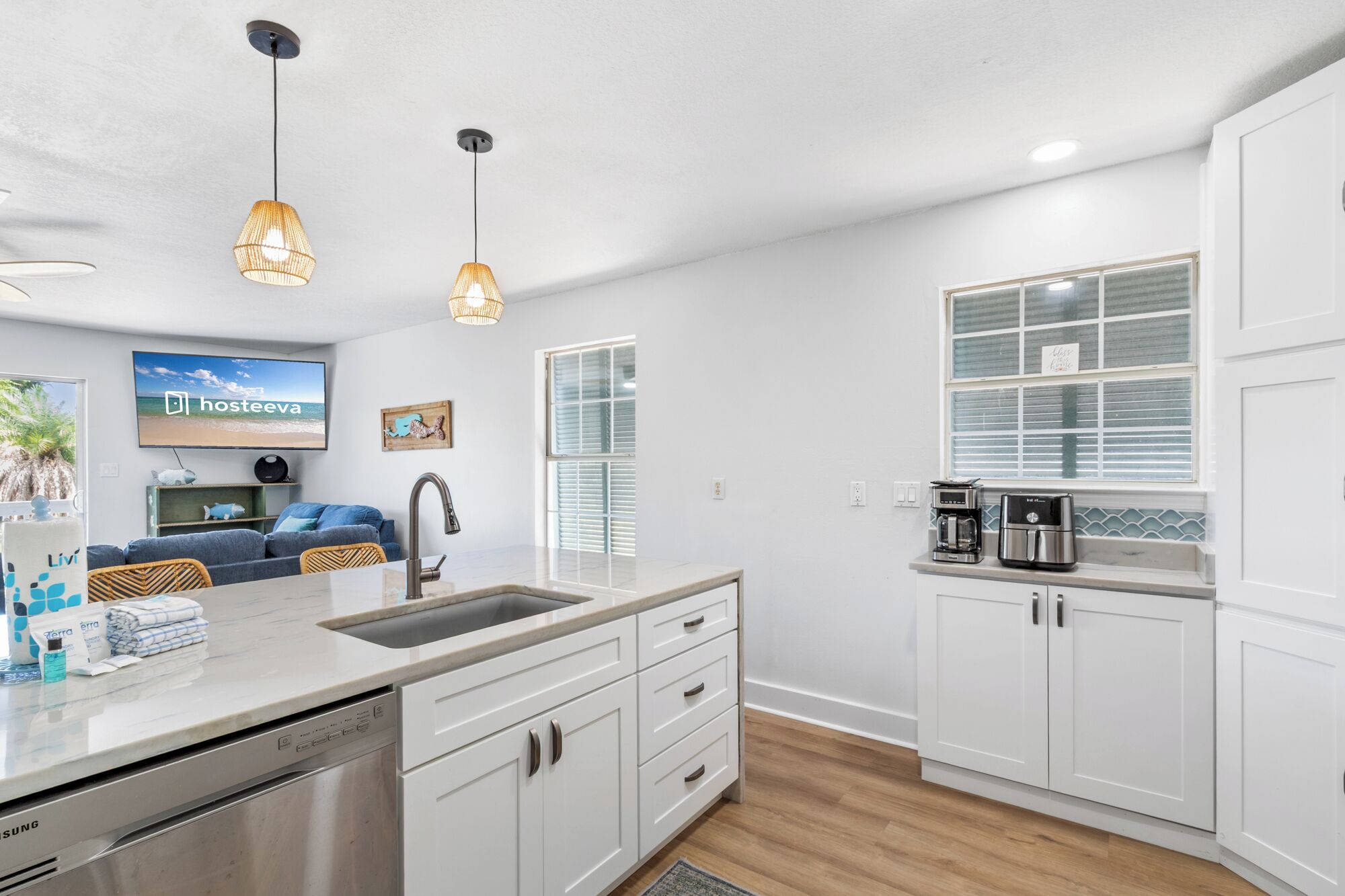 A modern kitchen with white cabinets, a stainless steel dishwasher, and a coffee maker on the counter.
