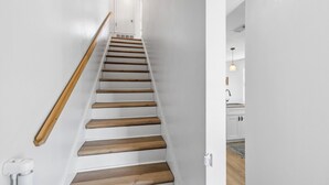 A staircase with wooden steps and a wooden handrail, leading to a white door at the top.