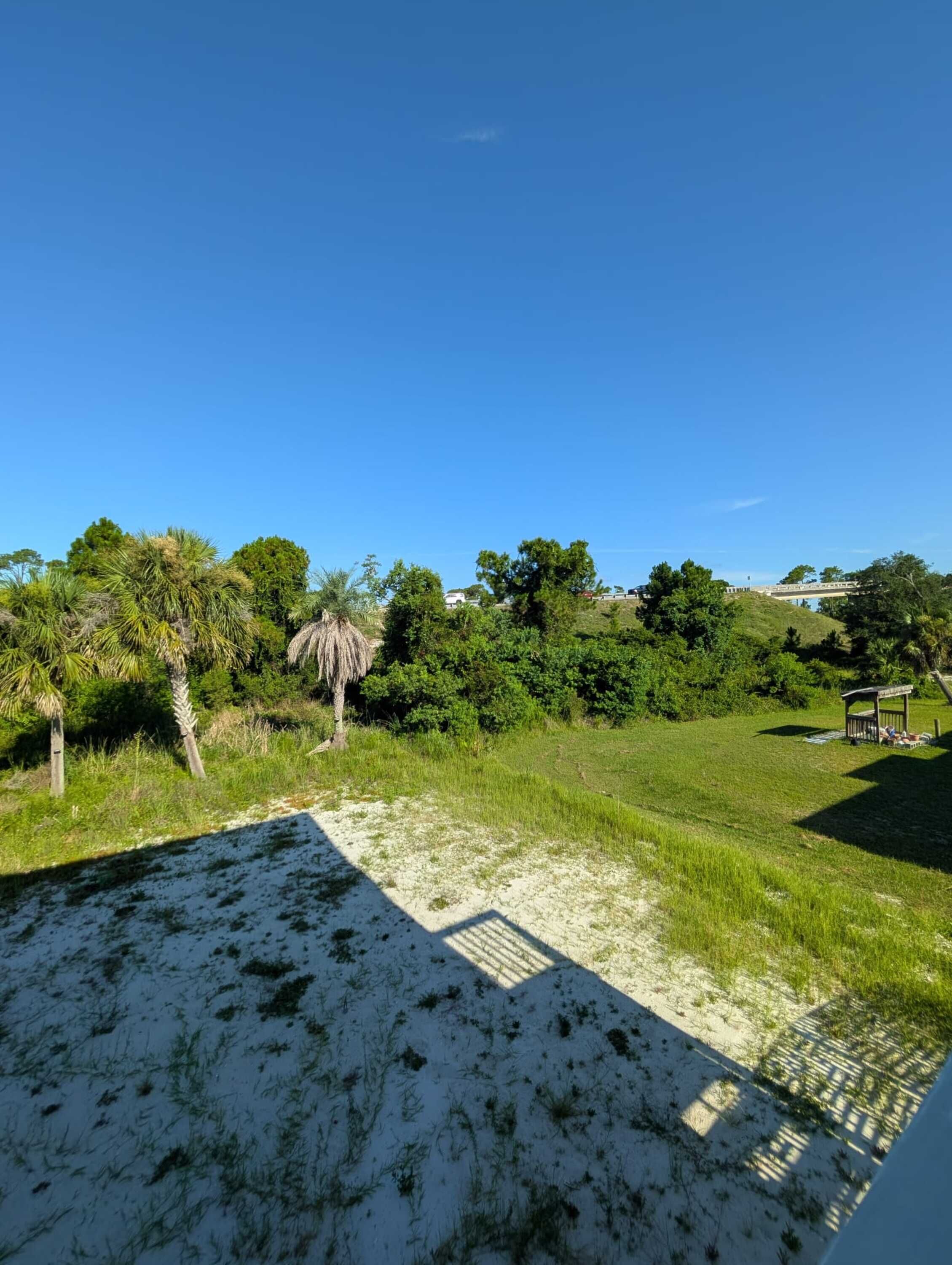 A beach with a thatched structure and a clear blue sky.