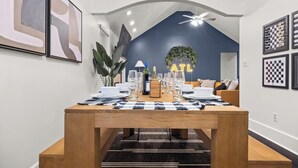 Un comedor moderno con una mesa de madera preparada para cuatro personas, un letrero de neón que dice