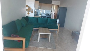 Una sala de estar con un sofá seccional verde, una mesa de centro de madera y una alfombra estampada.