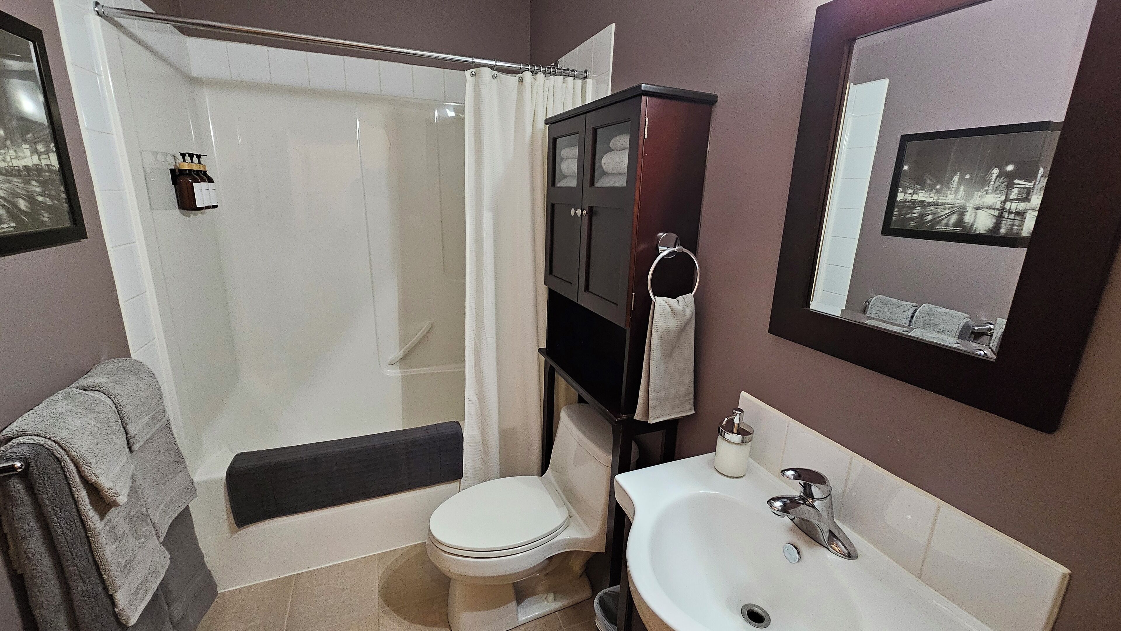 Un baño con ducha, inodoro, lavabo y espejo que ofrece vistas a la ciudad.