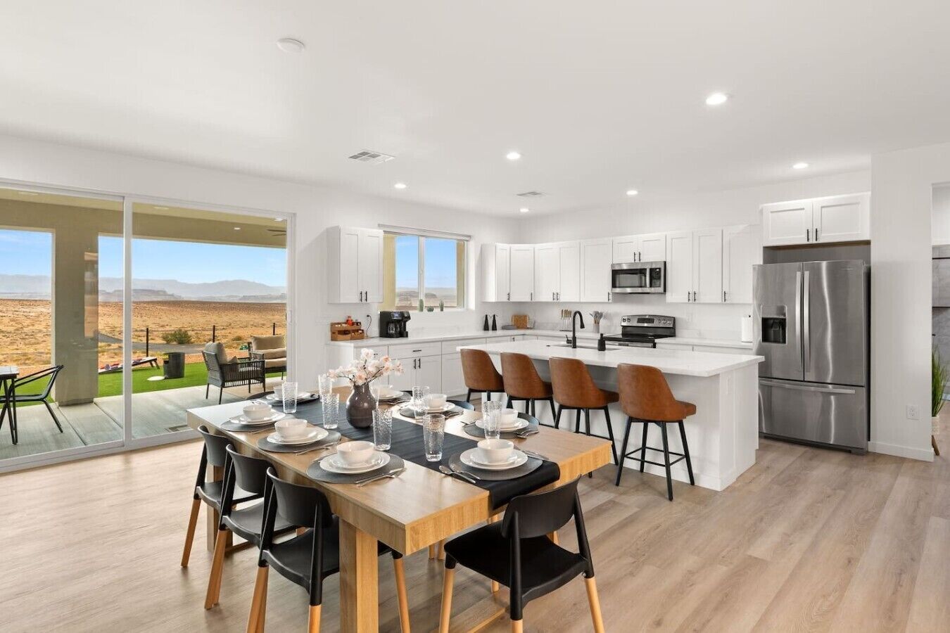 A modern kitchen with a central island, stainless steel appliances, and a dining area with a view of the desert.
