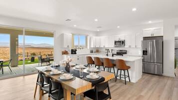 A modern kitchen with a central island, stainless steel appliances, and a dining area with a view of the desert.