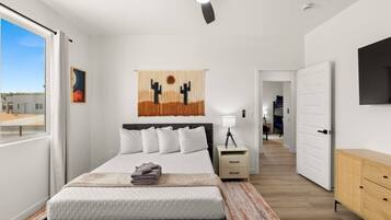 A modern bedroom with a bed, bedside table, and a ceiling fan.