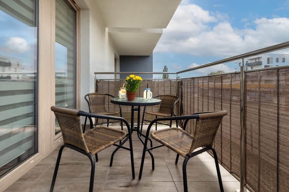 Ein Balkon mit Korbstühlen, einem runden Tisch und einem Blumentopf.