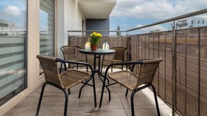 A balcony with wicker chairs, a round table, and a potted plant.