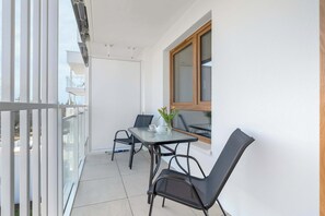 A balcony with a table and chairs, a window, and a view of the outside.