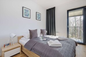 A modern bedroom with a bed, bedside table, and a window with curtains.