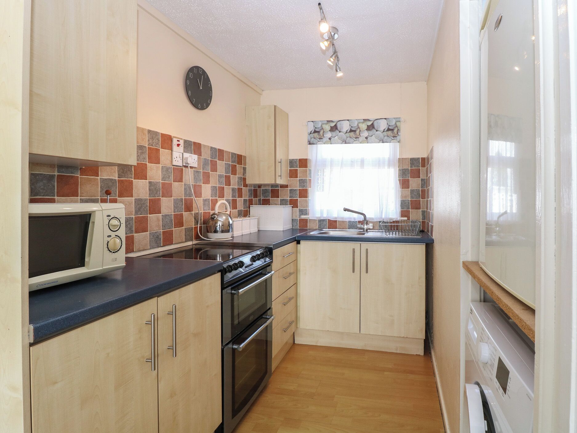 A compact kitchen with a microwave, stove, oven, and a sink.
