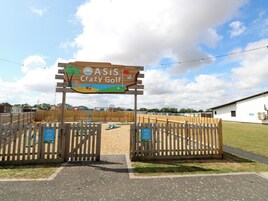 Um portão de madeira com uma placa indicando ASiS Crazy Golf.