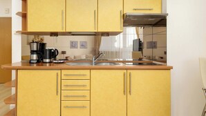 Una cocina con gabinetes amarillos, un lavamanos de acero inoxidable y una cafetera.