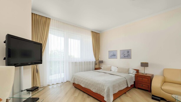 Un dormitorio moderno con cama, mesitas de noche, televisor y sofá.