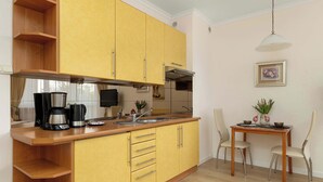 Una cocina con armarios amarillos, encimera de madera, cafetera y una mesa de comedor con sillas.