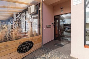 En träingång med en skylt som visar texten ”Tavern Pacyk” och siffran ”18” på väggen.