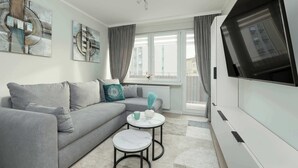 A modern living room with a grey sofa, a small round table, and a flat-screen TV.