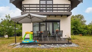 Ein zweistöckiges Haus mit Balkon, Außenbereich zum Sitzen und einem Trampolin.