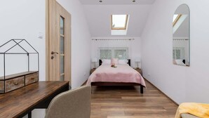 Ein Schlafzimmer mit Bett, Schreibtisch, Stuhl, Spiegel und einem Oberlicht.