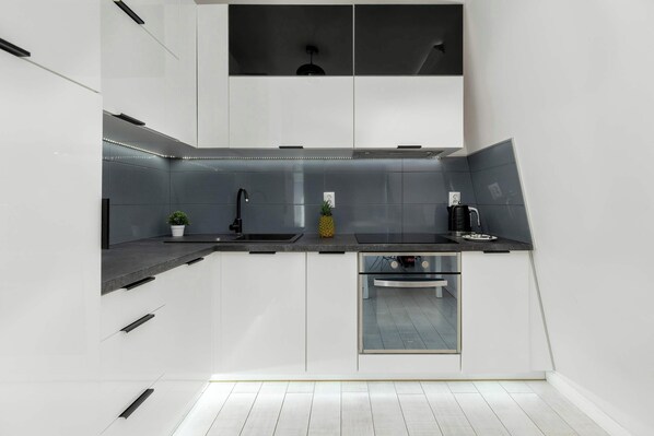Una cocina moderna con armarios blancos, un lavamanos de acero inoxidable y un horno empotrado.