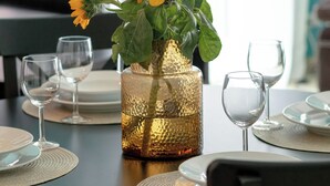 A dining table set with plates, cutlery, and a vase with flowers.