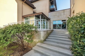 A set of concrete stairs leading to a building entrance with glass doors and a metal railing.