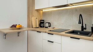 A kitchen with a wooden countertop, a sink, a coffee maker, and a bowl of fruit.