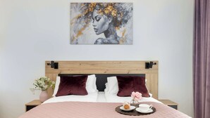 A neatly made bed with a pink quilt, a wooden headboard, and a side table with a vase of flowers.
