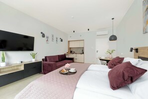 Moderni hotellihuone, jossa on sänky, työpöytä, sohva ja televisio.