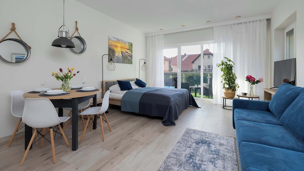 Una sala moderna con una cama, un sofá, una mesa de comedor con sillas y un televisor.