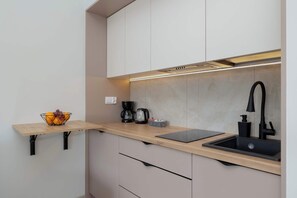 A modern kitchen with a wooden countertop, black faucet, and a coffee maker.