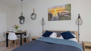 Un dormitorio con cama, mesitas de noche, un escritorio con sillas y un cuadro en la pared.