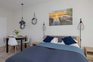 A bedroom with a bed, bedside tables, a desk with chairs, and a painting on the wall.