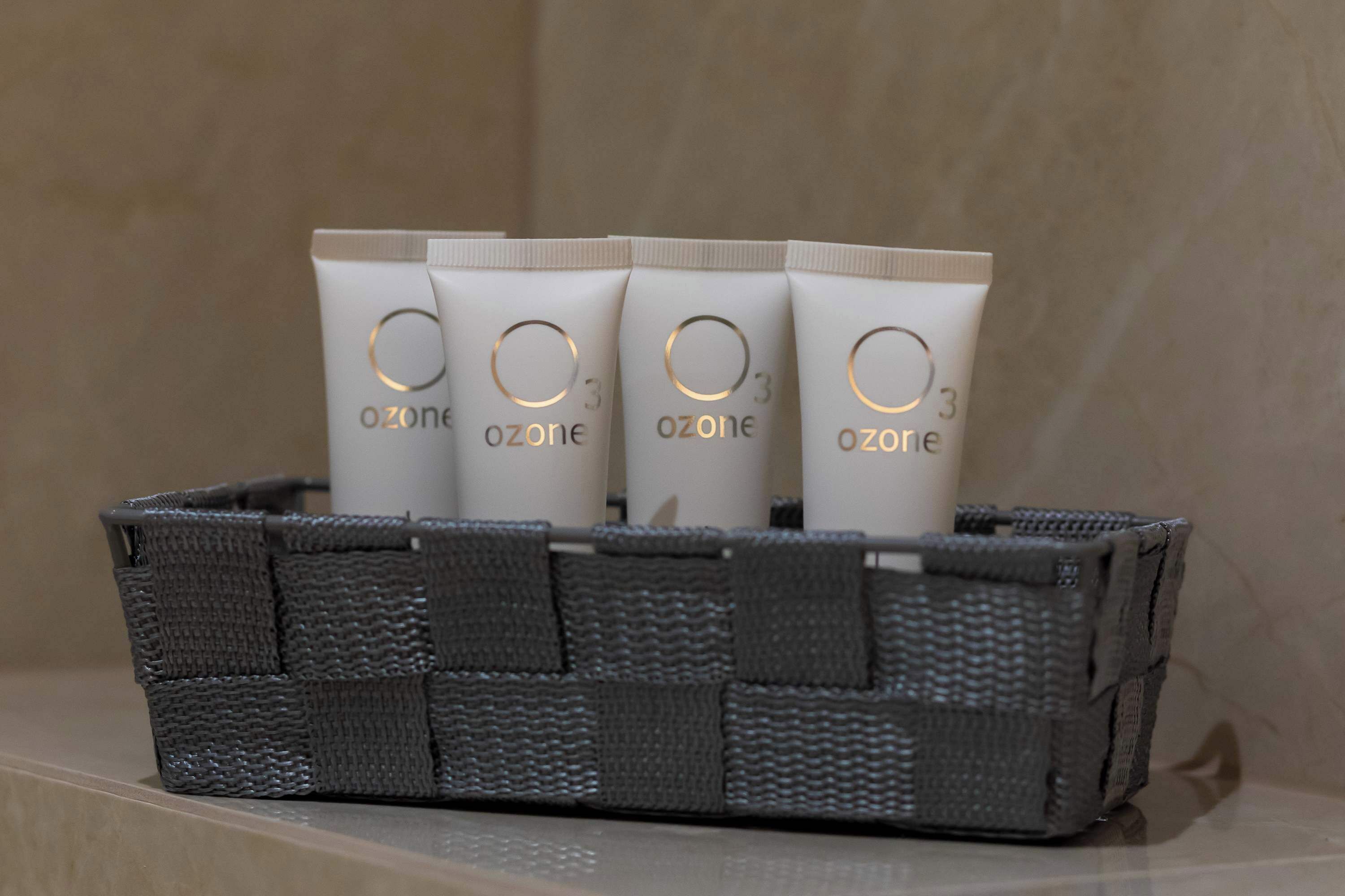 Ein grauer gewebter Korb mit vier weißen Röhren, beschriftet mit 'ozone', und einem goldenen Logo.